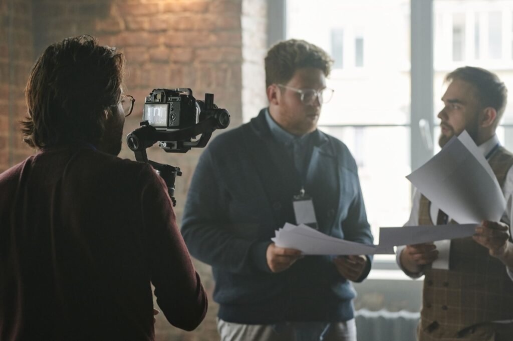 A professional team in a modern office setting being filmed during a business discussion.
