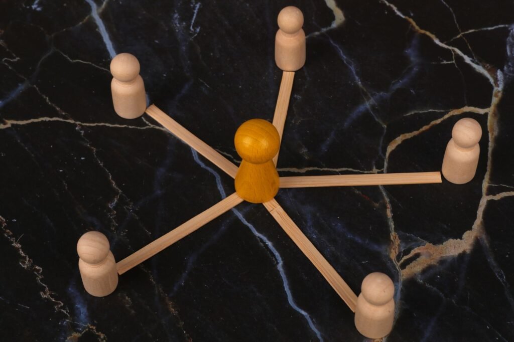 Wooden figures arranged in network pattern on dark marble background, symbolizing communication.
