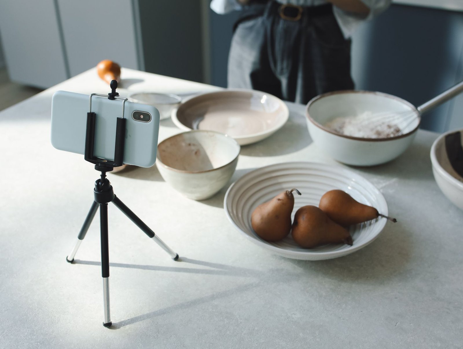 Cozy kitchen scene capturing baking preparations with smartphone tripod setup.
