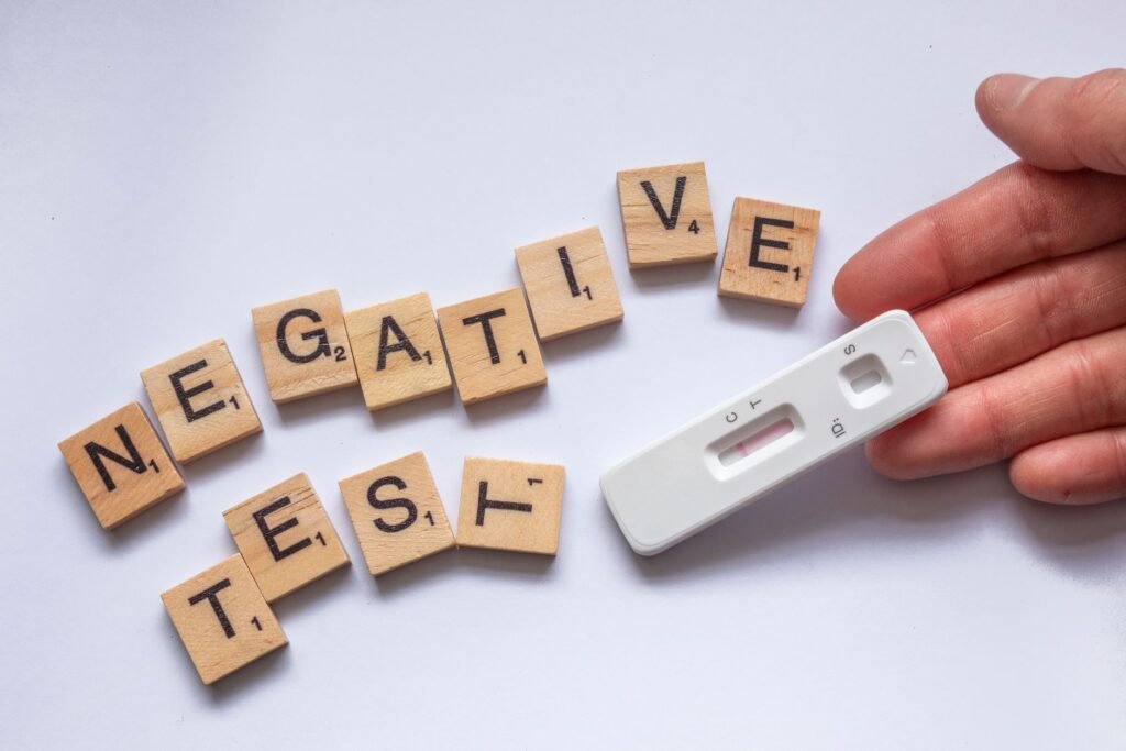 A negative test result displayed with scrabble letters and a test kit on a white surface.