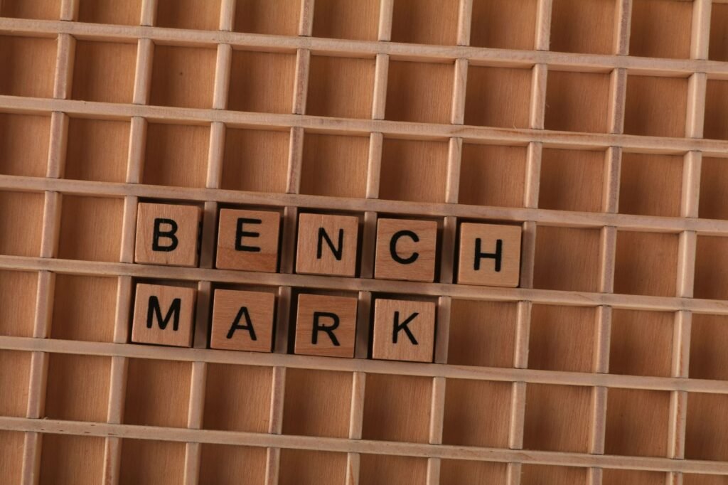 Wooden letter tiles spelling 'BENCHMARK' placed on a grid-like wooden background.