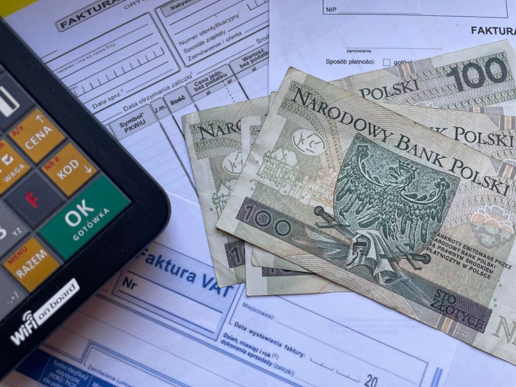 Polish currency placed on invoices with a calculator, illustrating financial transactions or budgeting.