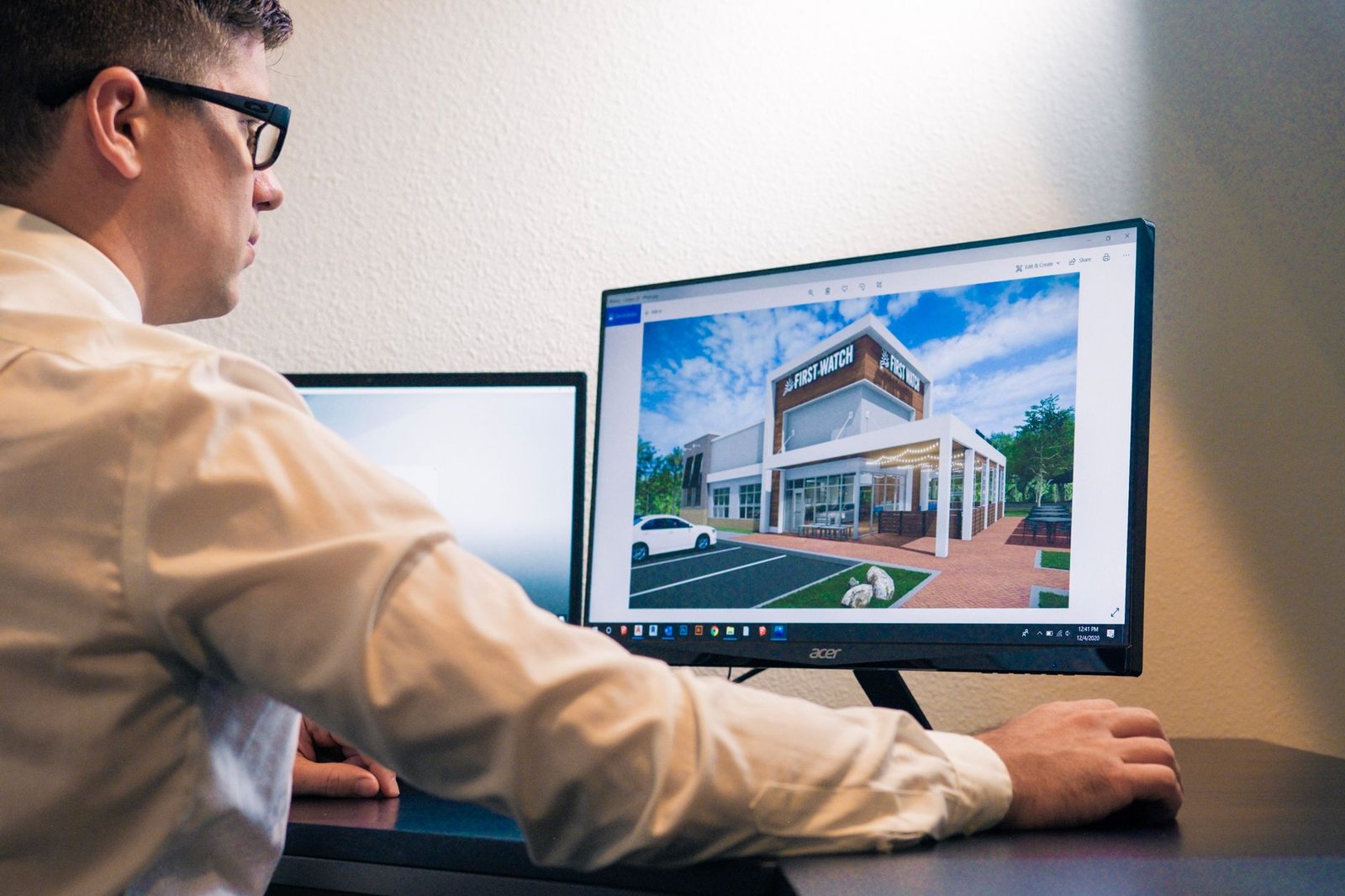 Architect evaluating a building design on a computer screen in an office setting.