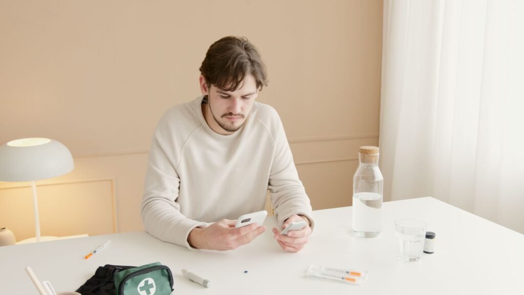 Young man checking glucose levels with a smartphone indoors at a home setting.