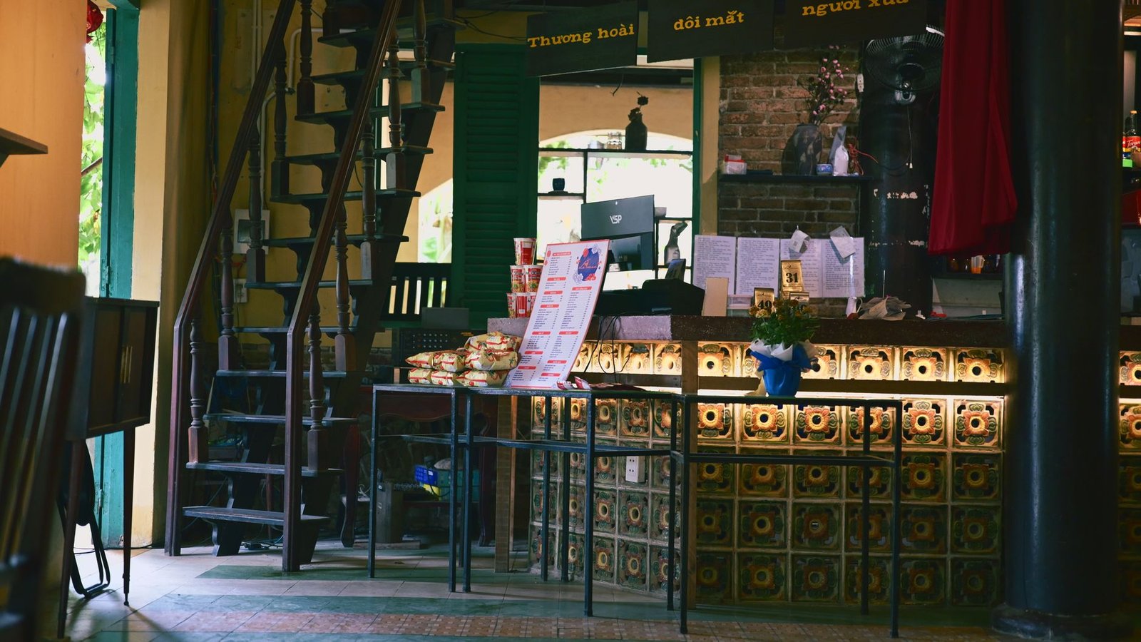 A warm and inviting cafe interior featuring a rustic staircase and illuminated counter.
