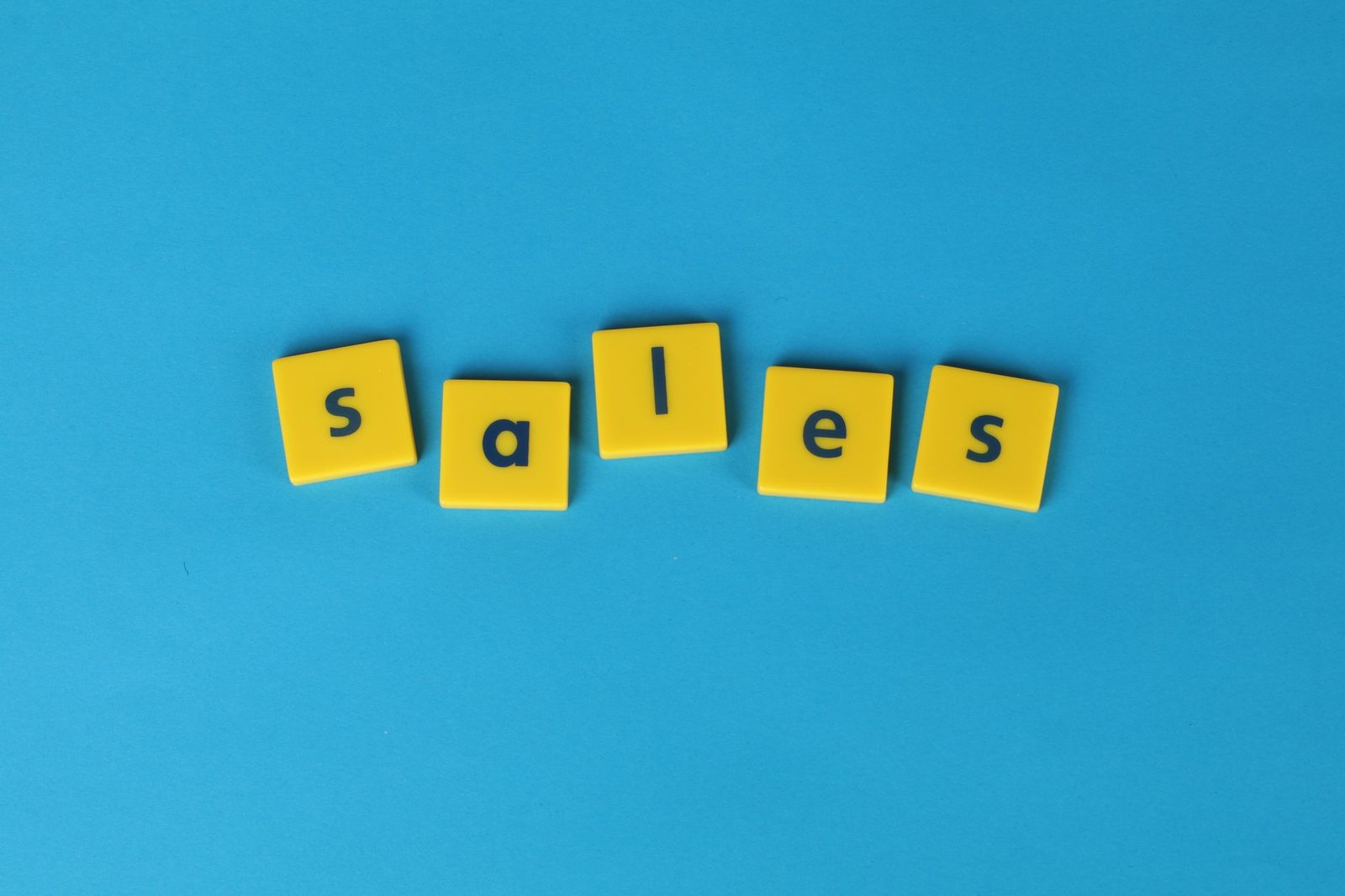 Yellow Scrabble tiles spelling 'sales' on a vibrant blue background. Perfect for marketing and business themes.