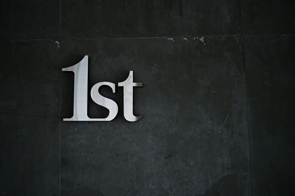 A close-up of '1st' metal lettering on a textured dark wall, offering a minimalist design.