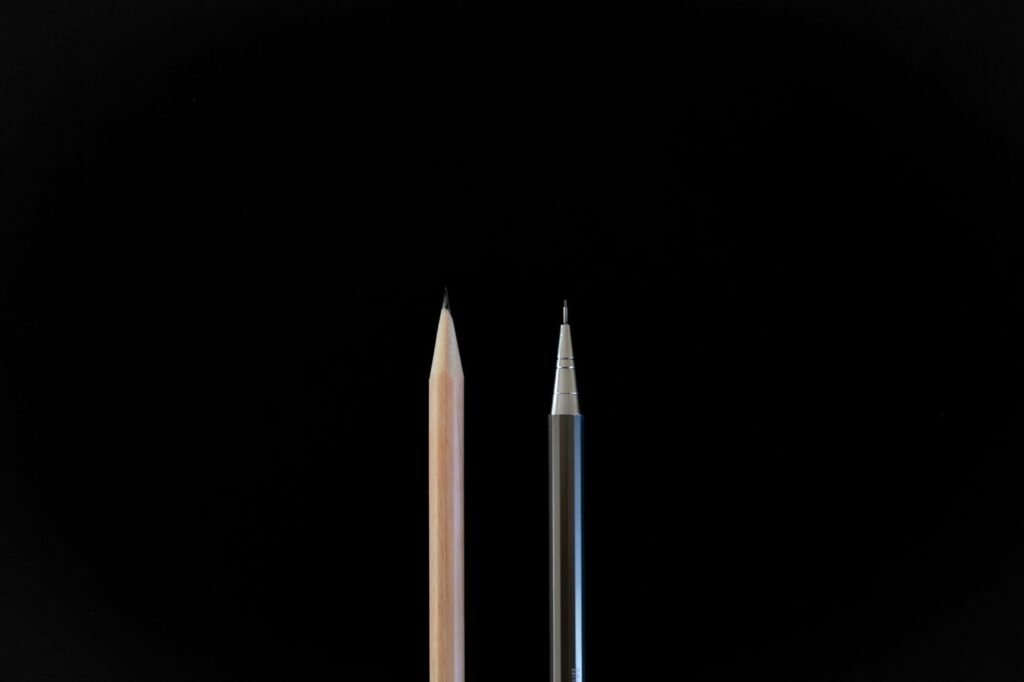 A clean, minimalist shot showcasing a traditional pencil and a mechanical pencil against a black background.