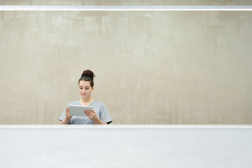 A receptionist in a modern office environment focused on a digital tablet.