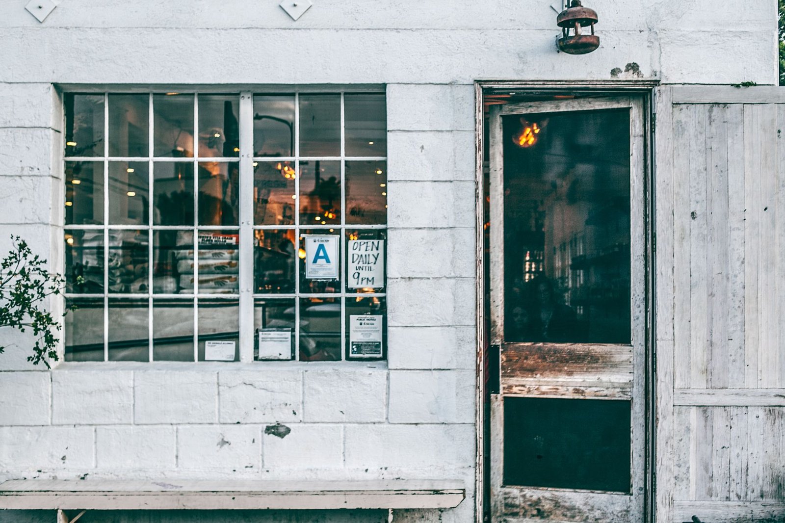 Exterior of aged shabby and dirty small shop with wooden door and hanging rusty lantern