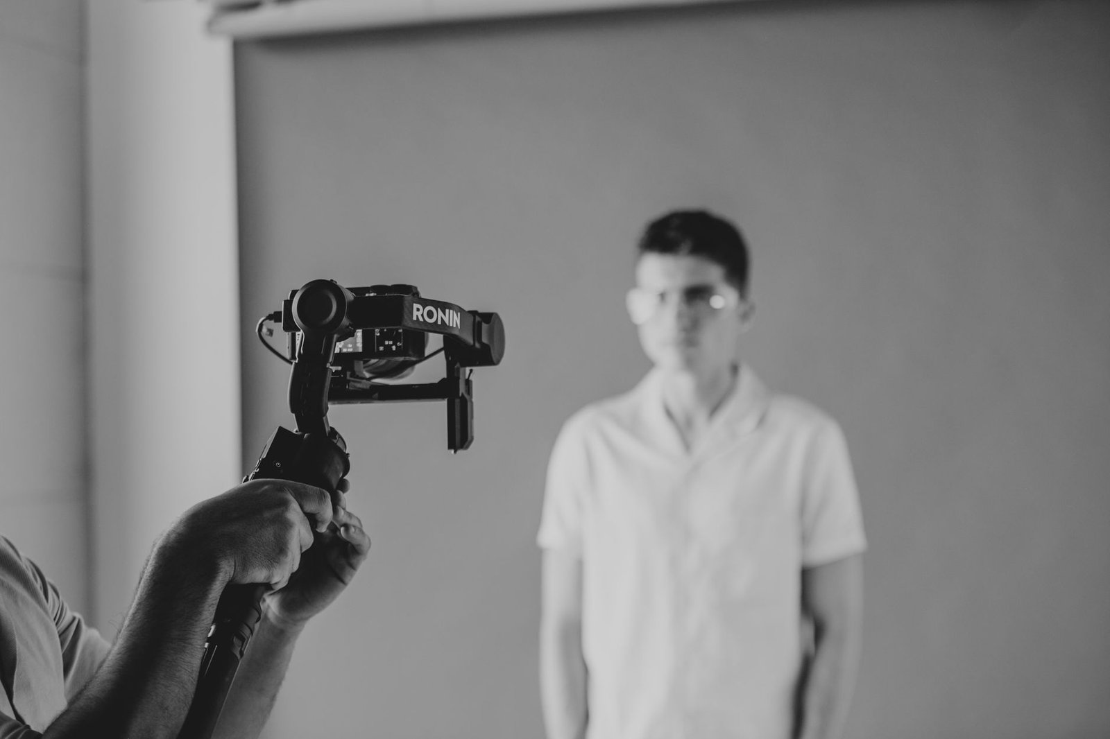 Monochrome image of a videographer using a stabilizer in a studio shoot.