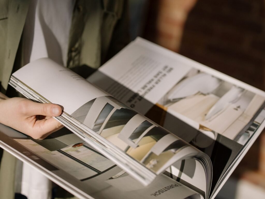 Close-up of hands turning pages in a modern architecture magazine.
