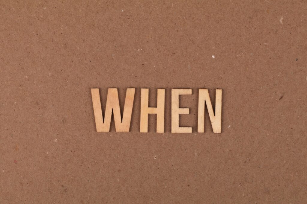 Wooden letters forming the word 'When' on a plain cardboard background.